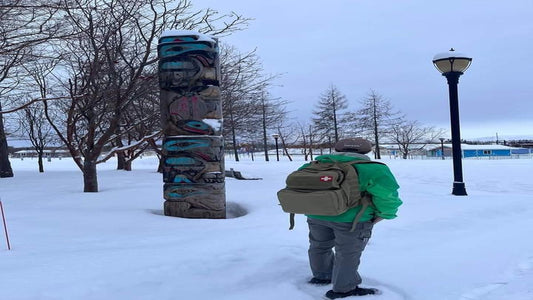 Squatch Survival Gear’s Mothman backpack, tested in Alaskan snow beside a totem pole, showcases rugged durability and tactical functionality. The ultimate water-resistant pack for extreme adventures.