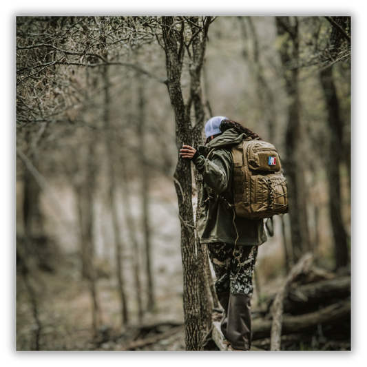 Female hiker in the woods wearing a Coyote Rougarou backpack from Squatch Survival Gear, prepared for bugging out with durable survival gear.