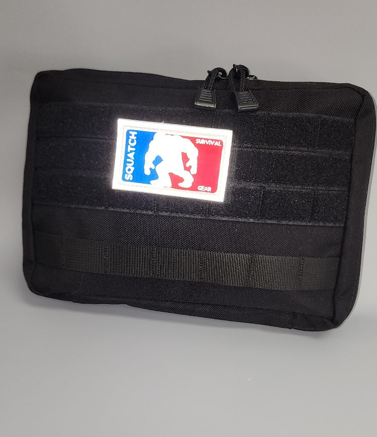 Squatch Survival Gear black admin pouch, 10 x 7 x 2 inches, made from durable 1000D material. The pouch is compact with a zippered closure, designed for tactical and everyday carry, shown with internal compartments for organized storage.